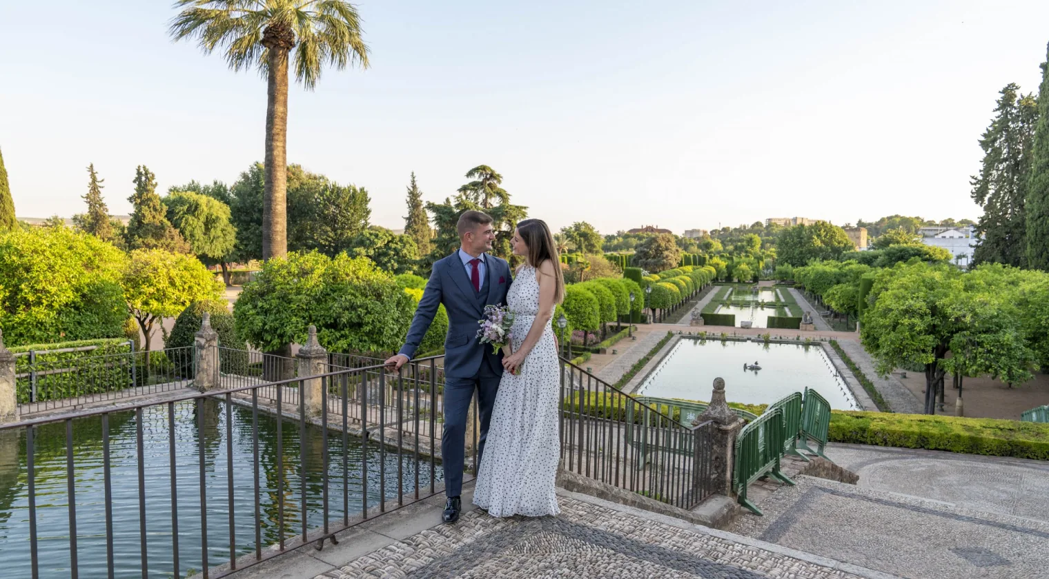 Pareja de novios en unos jardines con estanque, fotografía en exterior en Córdoba