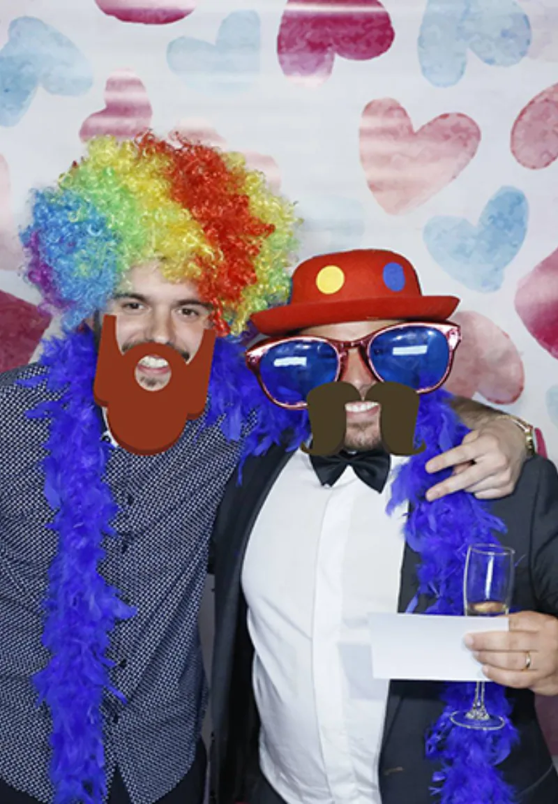 Invitados divertidos con pelucas y gafas en el fotomatón de boda